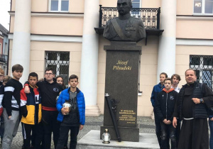 Uczniowie zapalają znicz pod pomnikiem Józefa Piłsudskiego